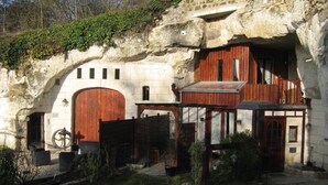 Un edificio rústico con un arco de piedra, puertas de madera y un pequeño jardín.