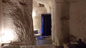 Una habitación que recuerda a una cueva, con una cama, una silla y un escritorio.