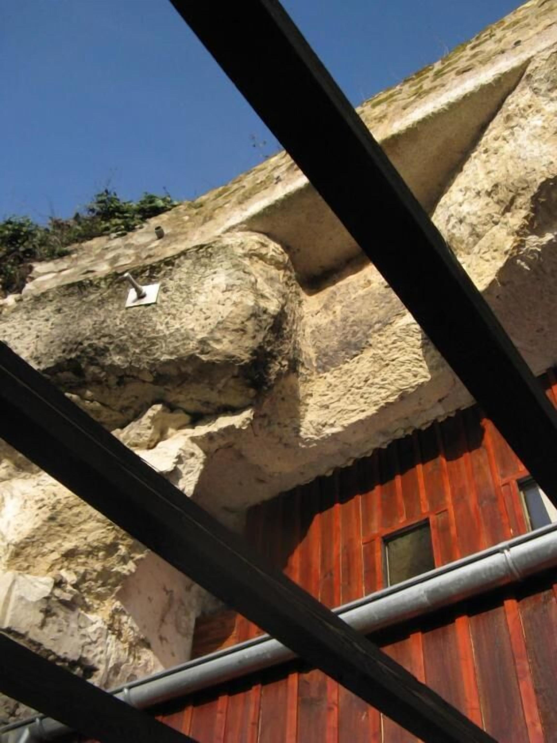 Un edificio rojo con fachada de piedra y una estructura metálica en primer plano.