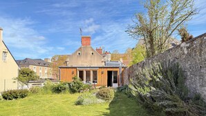 Ein Haus mit Garten, einer Steinmauer und blauem Himmel.