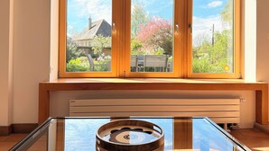 Ein Zimmer mit einem großen Fenster, einem Heizkörper und einem runden Tisch.