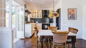 Een moderne keuken met witte kastjes, een zwart betegelde spatwand en een hangende glas-in-loodlamp.