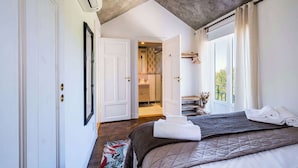 Een slaapkamer met een bed, een badkamer met een douche en uitzicht op de omgeving.