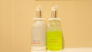 Dois frascos de produtos para cuidados com as mãos sobre uma superfície branca.