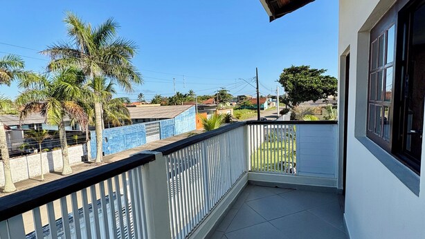 Een balkon met uitzicht op een zwembad, palmbomen en een heldere lucht.