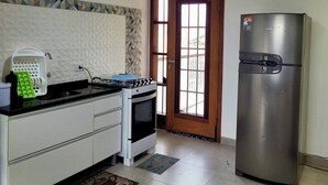 Een keuken met een fornuis, oven, koelkast en een raam met uitzicht.