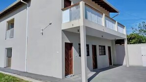 Een gebouw met twee verdiepingen, een balkon, een deur en een klein raam.