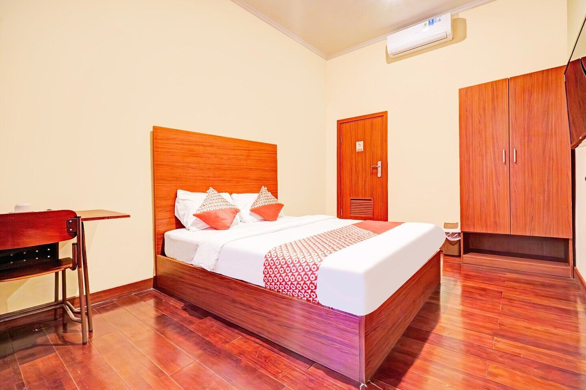 A hotel room with a wooden bed, a desk, and a wardrobe.