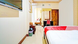 Una habitación de hotel con cama, escritorio, silla, armario y televisor.