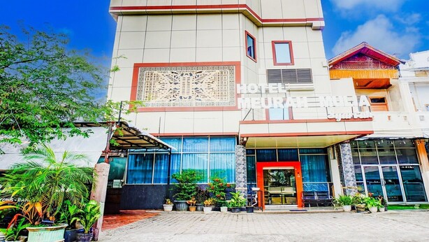 Een hotel genaamd 'Hotel Meurah Mulia' met een moderne gevel, grote ramen en een overdekt entreegebied.