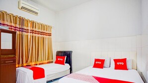 Een hotelkamer met twee bedden, een garderobe, een airconditioner en een gordijn.
