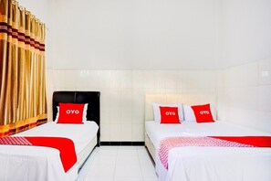 Une chambre d’hôtel avec deux lits, chacun doté d’un oreiller OYO rouge, de draps blancs et d’une tête de lit noire.
