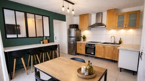 Una cocina moderna con armarios de madera, un refrigerador de acero inoxidable y un comedor con mesa y sillas de madera.