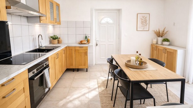 Una cocina moderna con armarios de madera, una estufa negra y un comedor con mesa y sillas de madera.