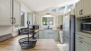 Eine moderne Küche mit hellen Schränken, einem Edelstahlkühlschrank und einem Holztisch.