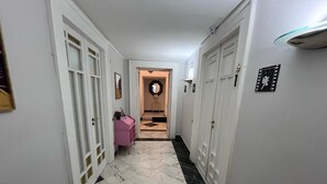 En hall med vita dörrar, en rosa byrå och en spegel på väggen.