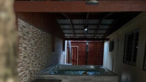 A spa area with a stone wall, a pool, and a wooden door. - Cozy house a few minutes from HOMS (Santiago de los Caballeros)
