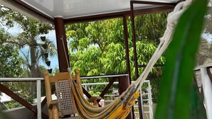 A room with a ceiling fan, a hammock, and a view of lush greenery outside. - Cozy house a few minutes from HOMS (Santiago de los Caballeros)
