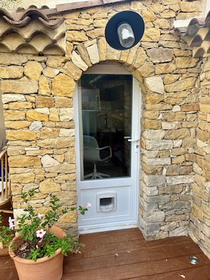 A stone wall entrance with a glass door, a potted plant, and a small porch area. - A charming house in the heart of Marseille with a sunny garden in a completely peaceful setting (Marseille)
