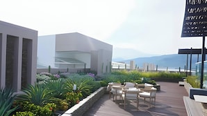 Une terrasse sur le toit avec des sièges en plein air, un bâtiment moderne et une vue sur les montagnes.