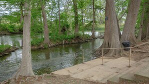 A concrete staircase leading down to a river, surrounded by trees and a metal railing. - Bluebonnet Poolside Paradise • Heated Pool • Schlitterbahn 5 Blocks • Sleeps 6 (New Braunfels)
