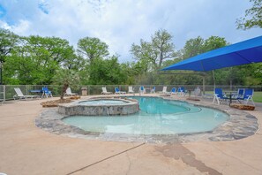 Une piscine bordée de pierres, entourée de chaises longues et dotée d’un espace abrité.