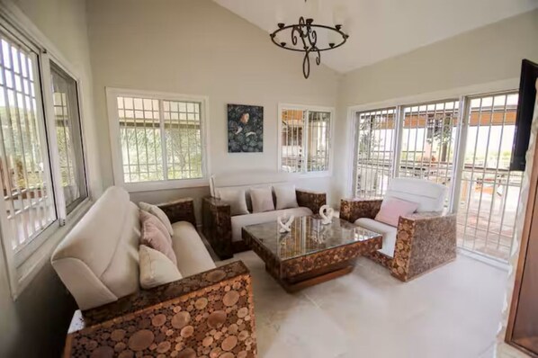 A spacious living room with a sofa, armchairs, a coffee table, and a chandelier. - Villa Armonía /Swimming Pool - Vista Verde - Santiago (Guayabal)
