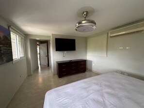 A bedroom with a bed, a dresser, a TV mounted on the wall, and a ceiling fan. - Villa Armonía /Swimming Pool - Vista Verde - Santiago (Guayabal)