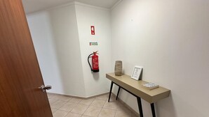 A hallway with a fire extinguisher, a sign, a vase, and a signboard on a table. - 2-bedr. apartment Palhinhas Historic Center 5 min. away (Albufeira)