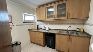 A kitchen with wooden cabinets, a sink, a window, and a trash bin. - 2-bedr. apartment Palhinhas Historic Center 5 min. away (Albufeira)