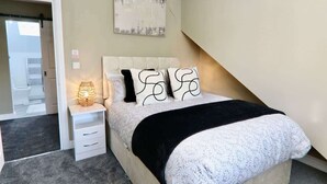 Ein Schlafzimmer mit Bett, Nachttischen, einer Lampe und einem Bild an der Wand.