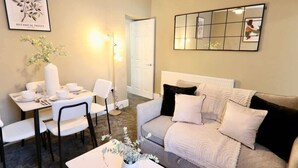 Ein Wohnzimmer mit einer Couch, einem Couchtisch, einem Esstisch mit Stühlen und einem Wandspiegel.