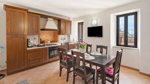 Une cuisine moderne avec des meubles en bois, une table à manger avec des chaises et un téléviseur fixé au mur.