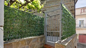 Un mur de pierre avec un portail en métal, un escalier et un mur recouvert de lierre.