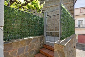 Un mur de pierre avec un portail en métal, un escalier et un mur recouvert de lierre.