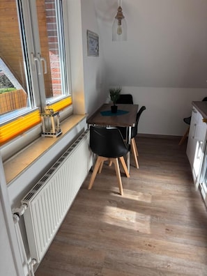 Eine moderne Küche mit Essbereich, Holzboden, Heizkörper und einem Fenster mit Blick.