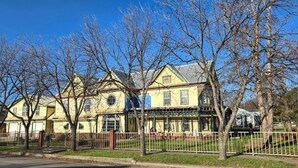 A two-story yellow house with a porch, surrounded by a fence and trees. - Welcome to our 1890 Victorian Mansion
Spacious 8-bedroom house in lovely Coleman (Coleman)