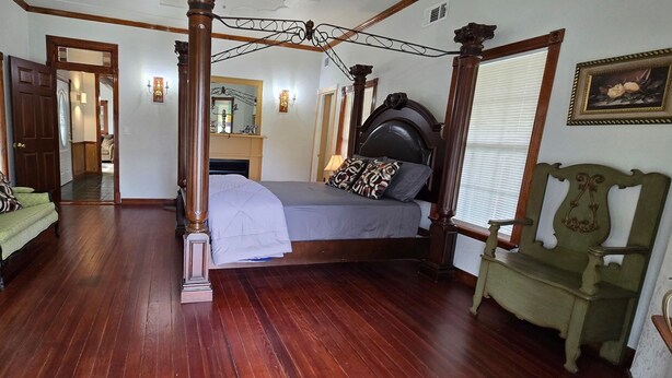 A room with a four-poster bed, a green sofa, a wooden chair, and a mirror on the wall. - Welcome to our 1890 Victorian Mansion
Spacious 8-bedroom house in lovely Coleman (Coleman)