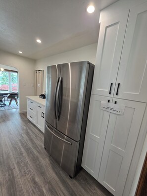 Una cocina moderna con un refrigerador de acero inoxidable, gabinetes blancos y un comedor con mesa y sillas.