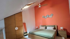 Un dormitorio con cama, mesitas de noche, ventilador de techo y un adorno en la pared.