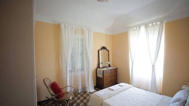 A bedroom with a bed, a dresser, a chair, and a mirror. - Au Petit Bonheur Apart (Rapallo)