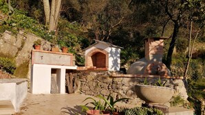 A rustic outdoor area with a stone wall, a small brick building, and potted plants. - Au Petit Bonheur Apart (Rapallo)
