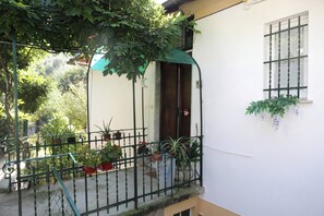 Ein Balkon mit Blumentöpfen, ein grünes Markisen und ein weißes Gebäude mit einem Fenster.
