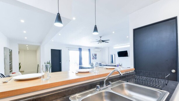 Une cuisine moderne dotée d’un grand évier, de deux suspensions et d’un ventilateur de plafond.