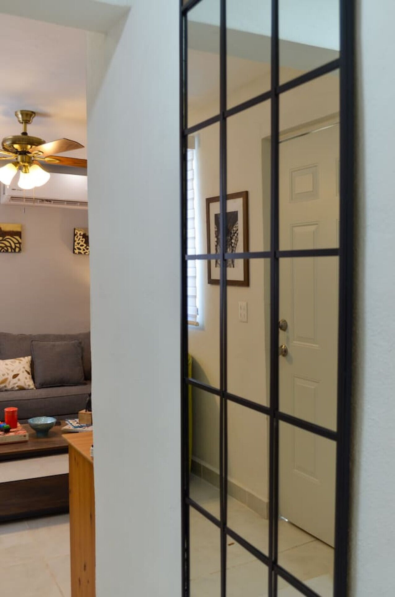 A room with a ceiling fan, a sofa, a coffee table, and a door with a grid pattern.