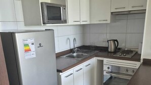 A compact kitchen with a refrigerator, microwave, stove, sink, and oven.