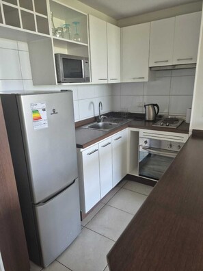 A compact kitchen with a refrigerator, microwave, stove, sink, and oven. - Modern Apartment - Steps away from Movistar Arena and Hipódromo (Santiago)