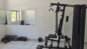 A gym with a weight bench, a squat rack, and various weights.