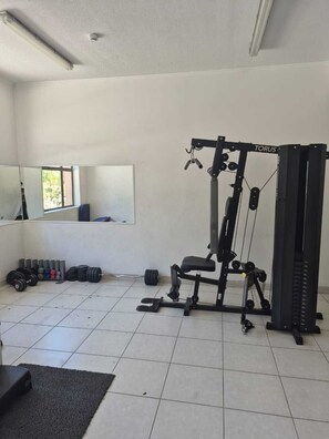 A gym with a weight bench, a squat rack, and various weights. - Modern Apartment - Steps away from Movistar Arena and Hipódromo (Santiago)