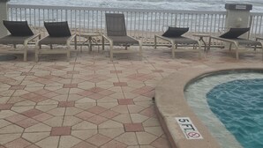 A beachside pool area with hexagonal tiles, lounge chairs, and a 'No Smoking' sign. - Cozy studio in a fantastic Daytona Beach location (Daytona Beach)